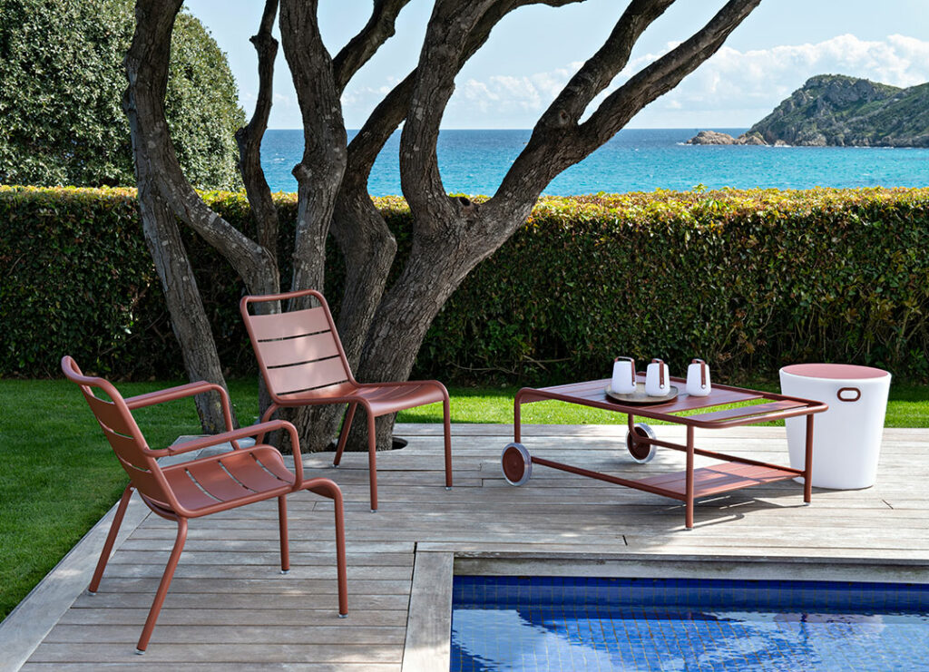 Une Table basse à roues Luxembourg et des chaises au bord d'une piscine.