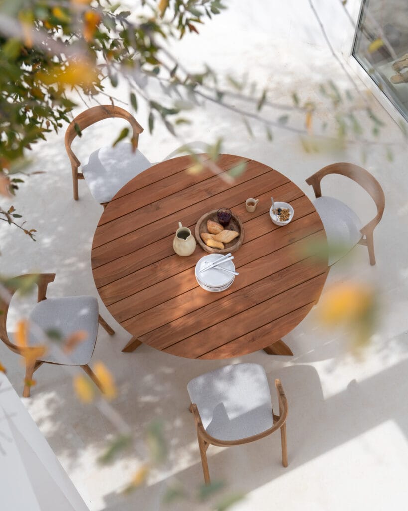 Une Table de jardin Circle en teck et des chaises sur un patio.