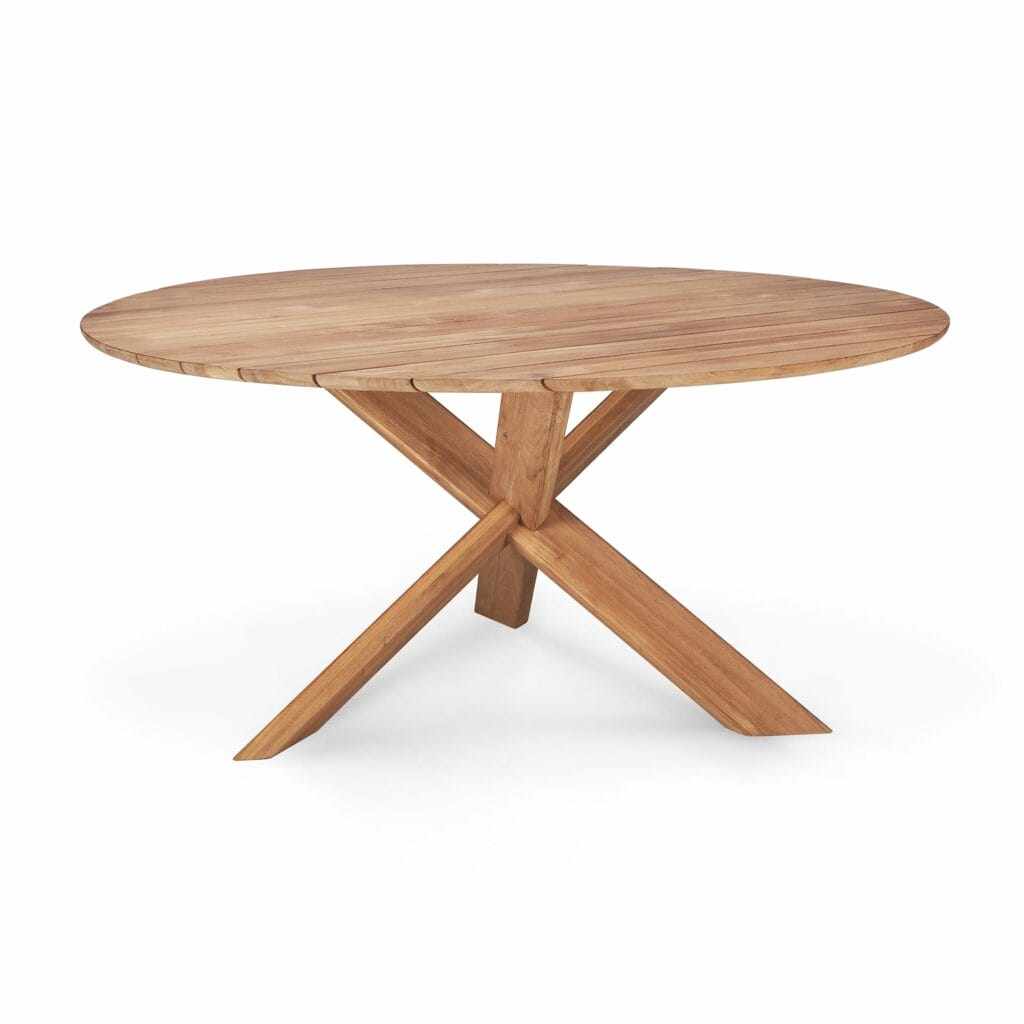 Une table de jardin Circle en teck avec des pieds croisés.