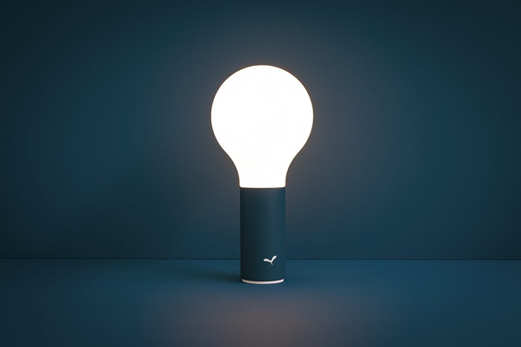 Une ampoule posée sur une surface sombre.