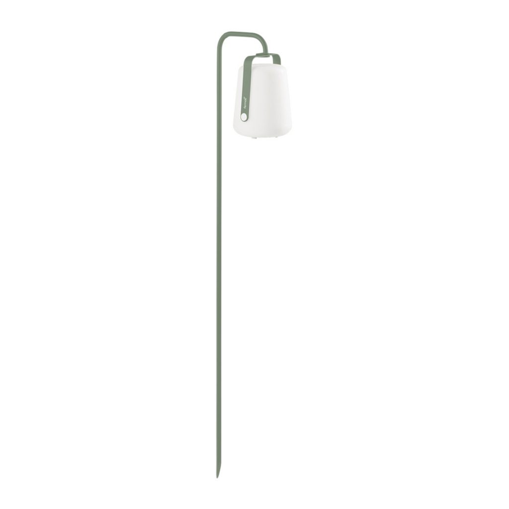 Une petite lampe avec un abat-jour vert sur fond blanc.