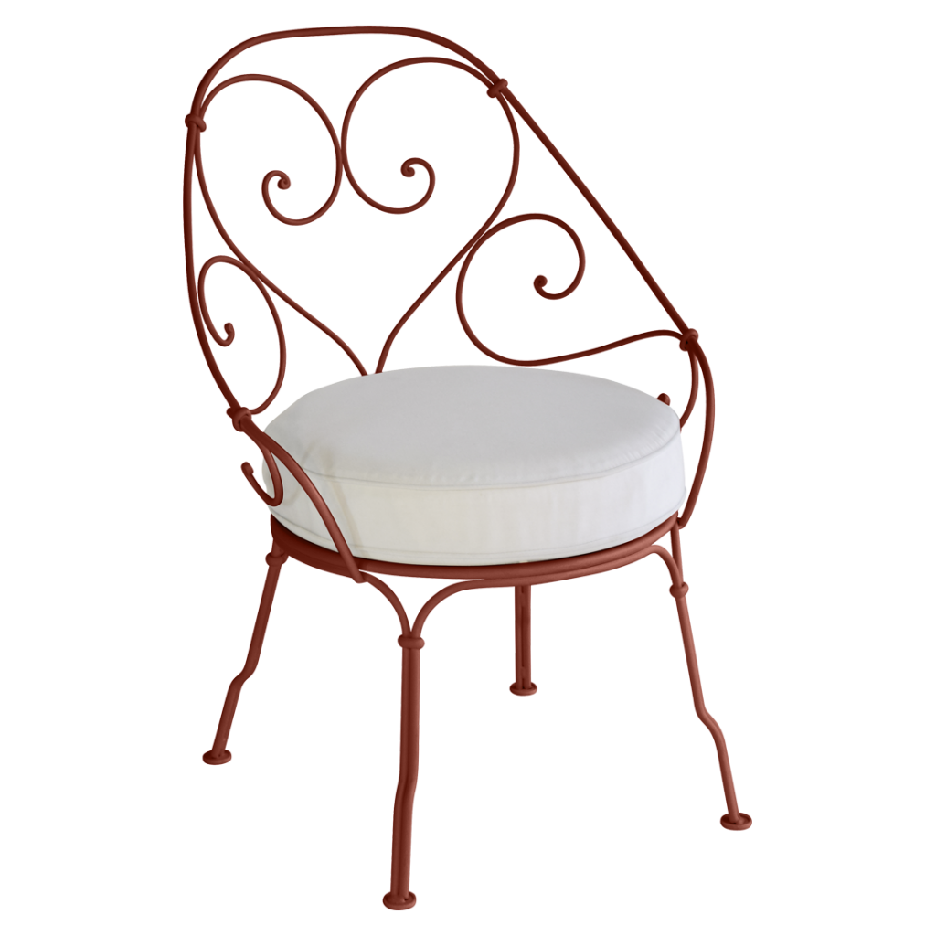 Une chaise en fer forgé rouge avec un coussin blanc.