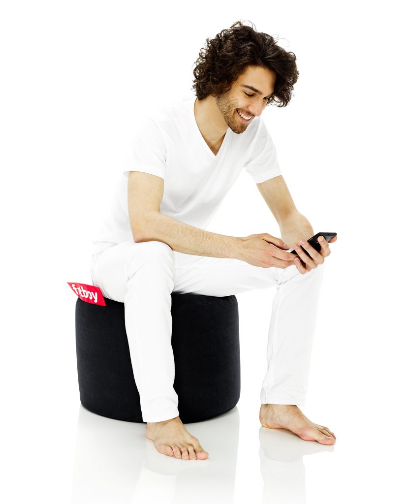 Un homme assis sur un pouf noir.