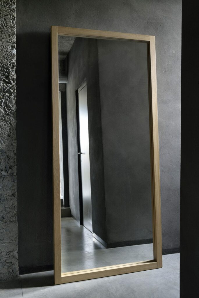 Une pièce spacieuse ornée d'un Miroir Light Frame, bénéficiant de son élégante construction Light Frame sur fond de murs en béton robustes.