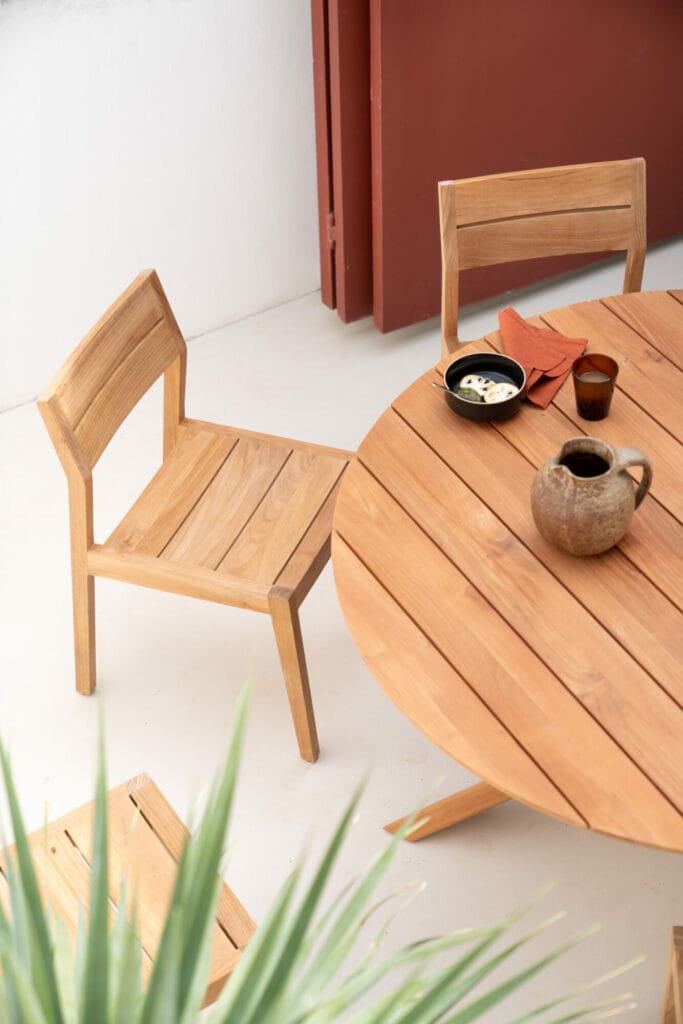 Une chaise de jardin EX1 en teck sur un patio.