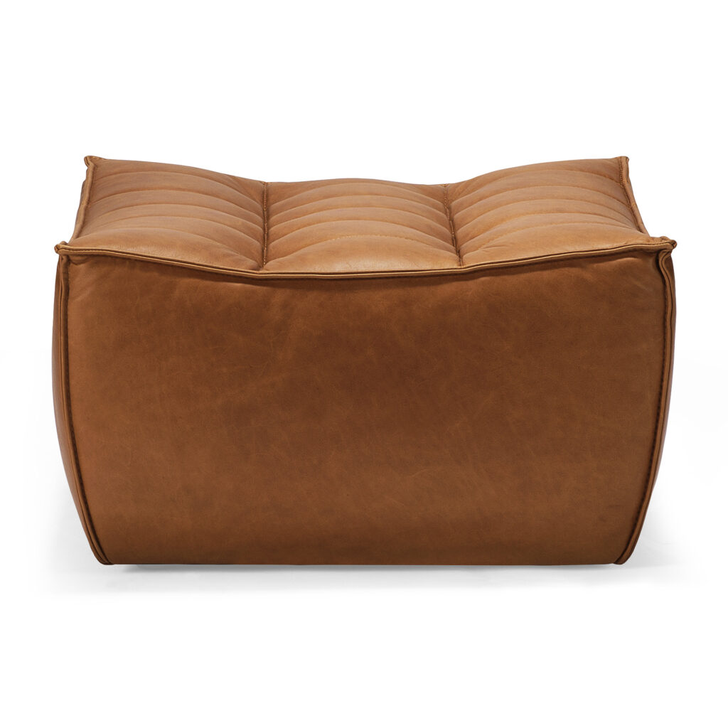 Pouf N701 en cuir marron, finition Old Saddle, avec surpiqûres apparentes et plateau touffeté en forme de coussin, présenté comme un élégant repose-pieds sur fond blanc.