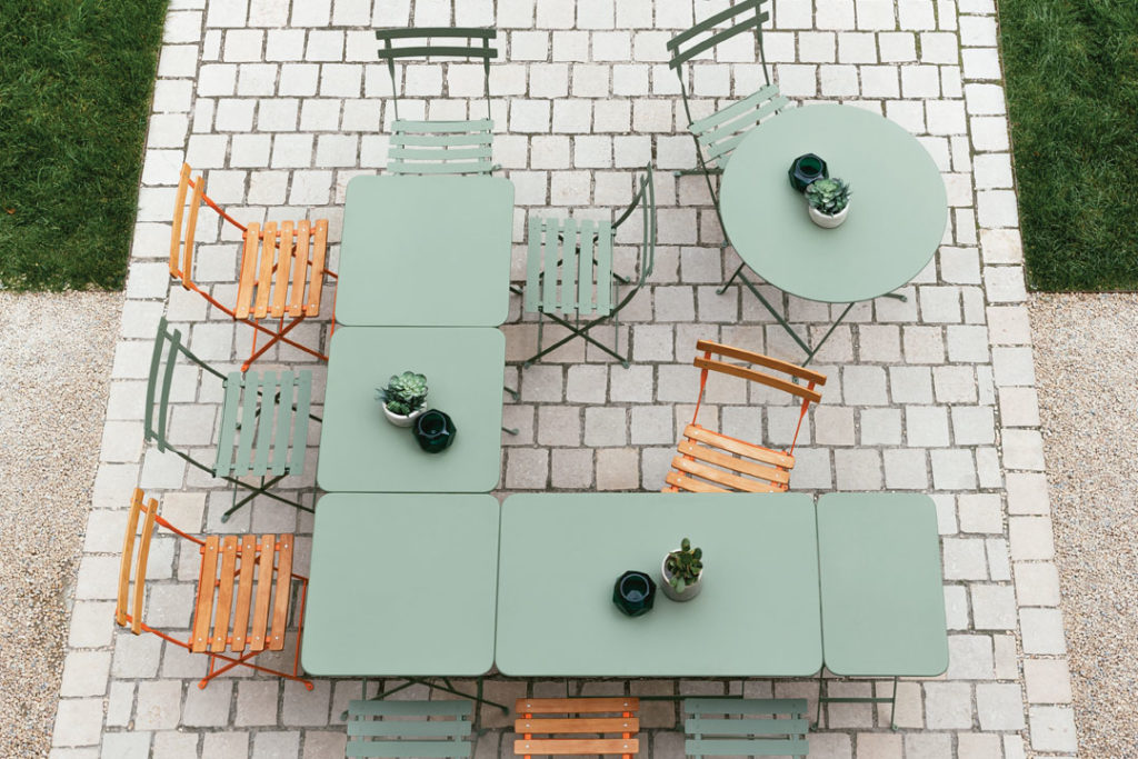 Une Table Bistro rectangulaire, 97 x 57 cm sur une terrasse en brique.