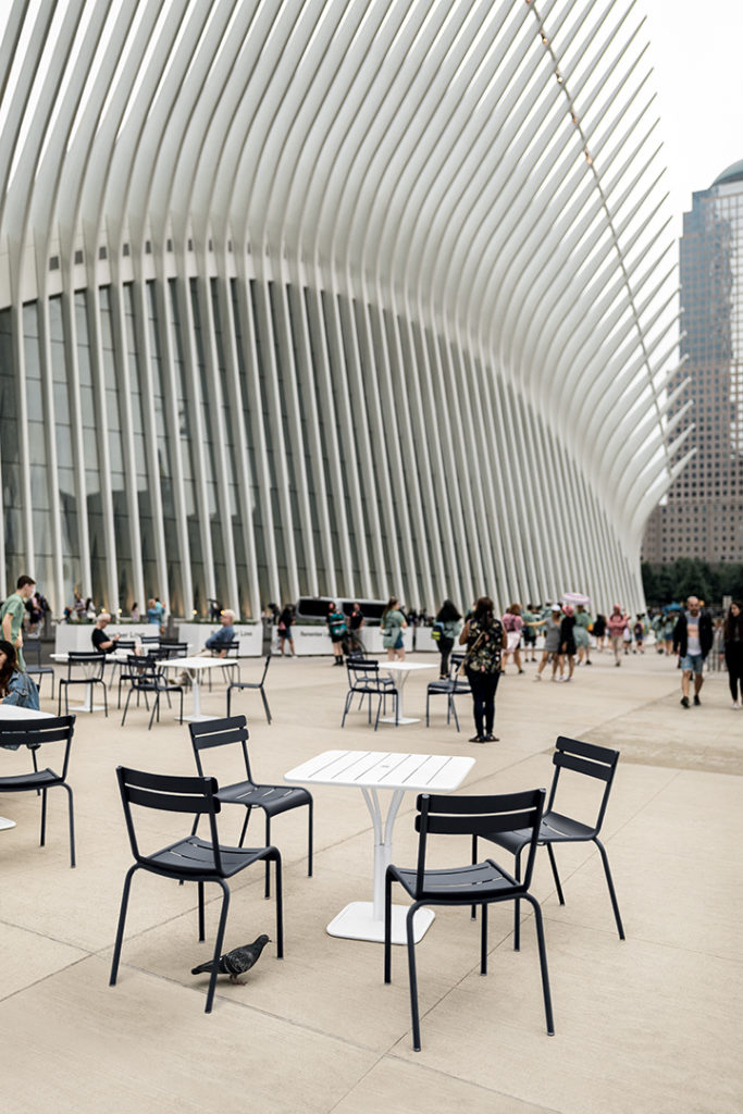 Table carree de jardin luxembourg gueridon 80x80 en aluminium laque couleur blanc coton et reglisse a New York dans un grand espace rempli de gens