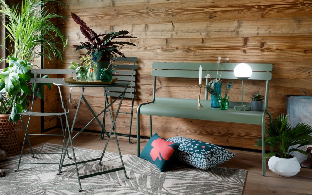 Un banc vert avec une plante dessus.