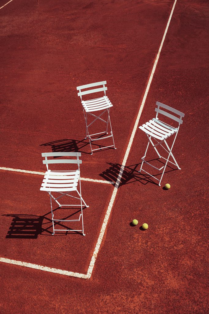 Trois chaises sur un court de tennis avec des balles de tennis.