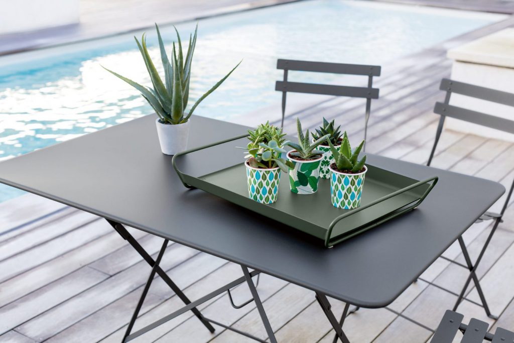 Une table et des chaises avec des plantes en pot et une piscine en arrière-plan.