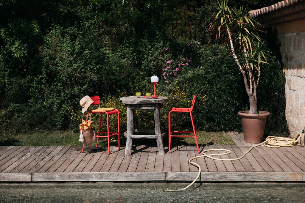 Une terrasse en bois avec une table et des chaises au bord d'une piscine.