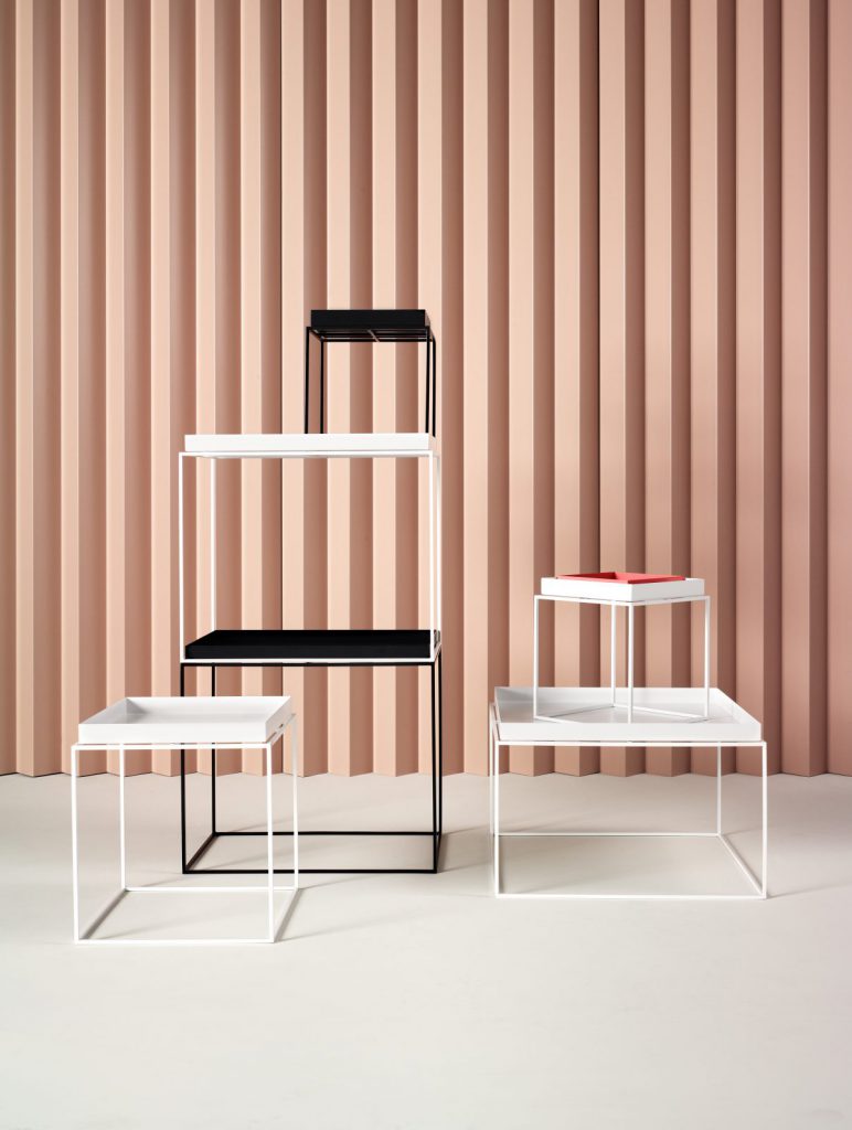 Trois tables d'appoint en noir et blanc devant un mur rose.