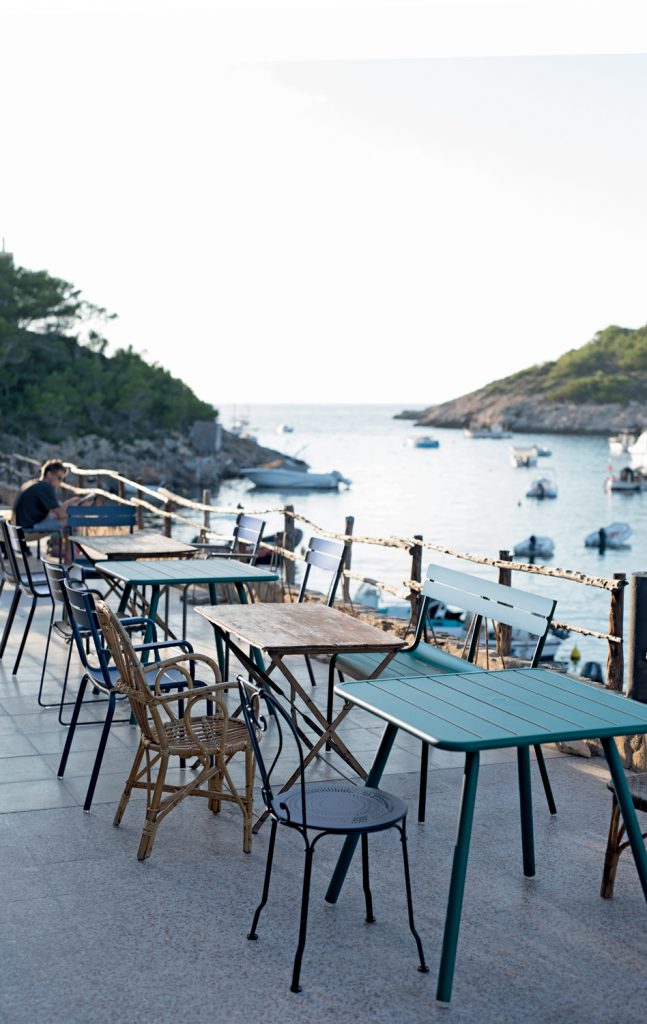 Un groupe de tables et de chaises sur un balcon donnant sur l'eau.
