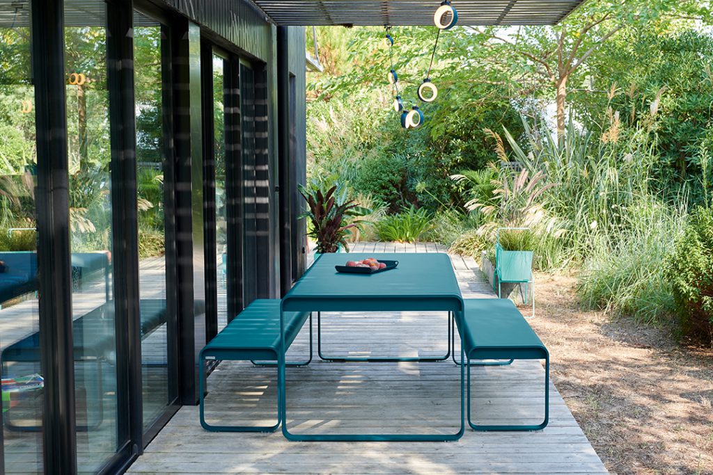 Une table et des chaises bleues sur une terrasse en bois.