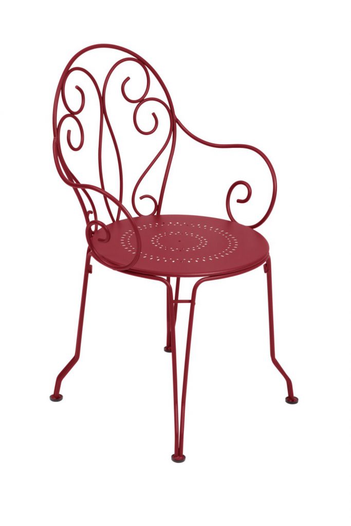 Une chaise en fer forgé rouge sur fond blanc.