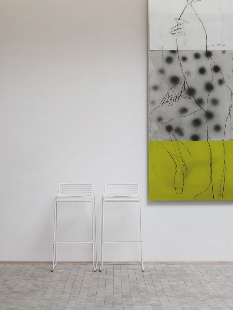 Deux tabourets et un tableau dans une pièce blanche.