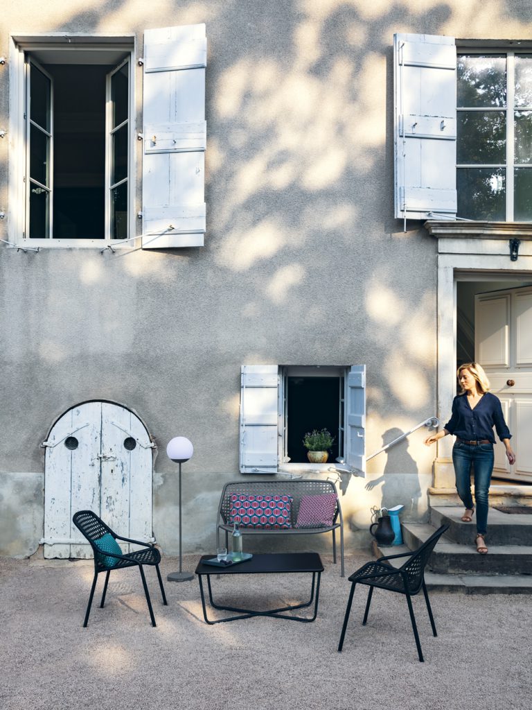 Une femme se tient devant une maison.