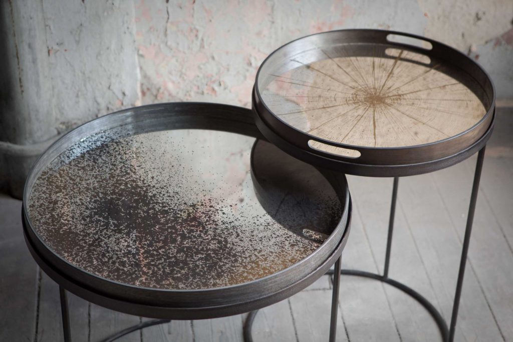 Deux tables d'appoint en miroir sur un parquet en bois.