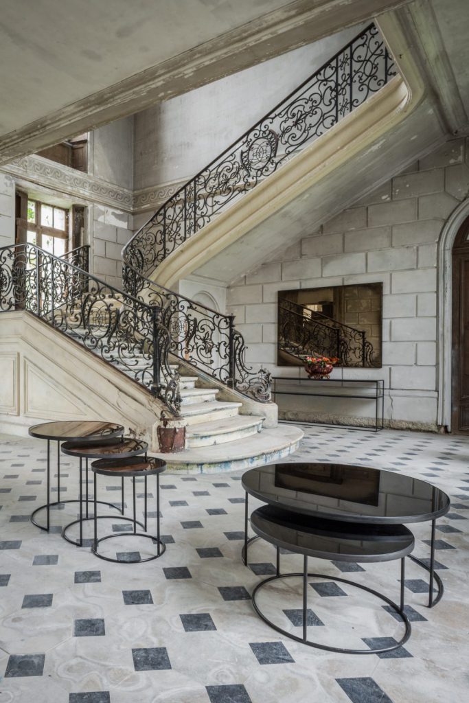 Une grande pièce avec un escalier et une rampe en fer forgé.