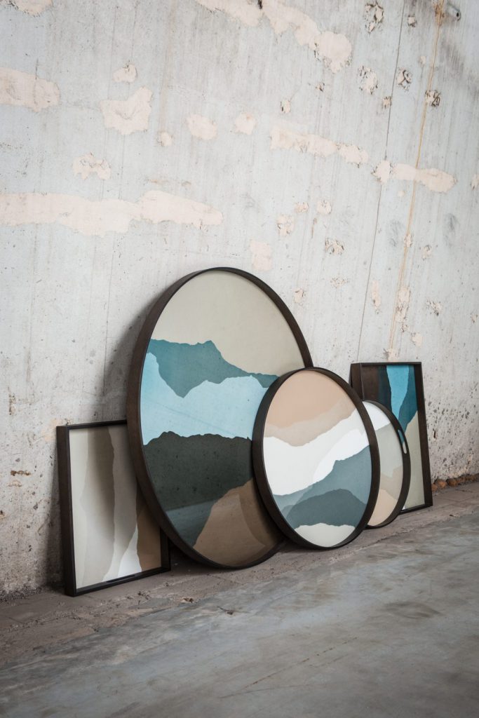 Un groupe de peintures sur un mur à côté d'un mur de béton.