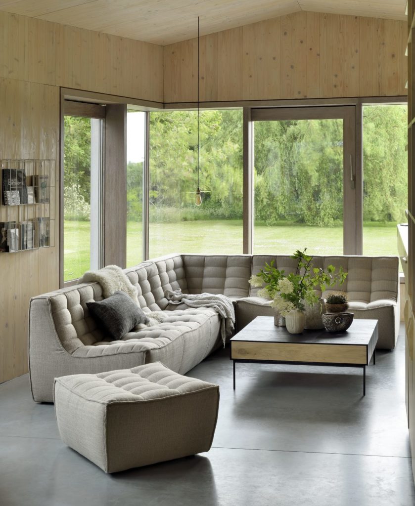 Un salon avec de grandes fenêtres et un plancher en bois qui dégage une esthétique manifeste.