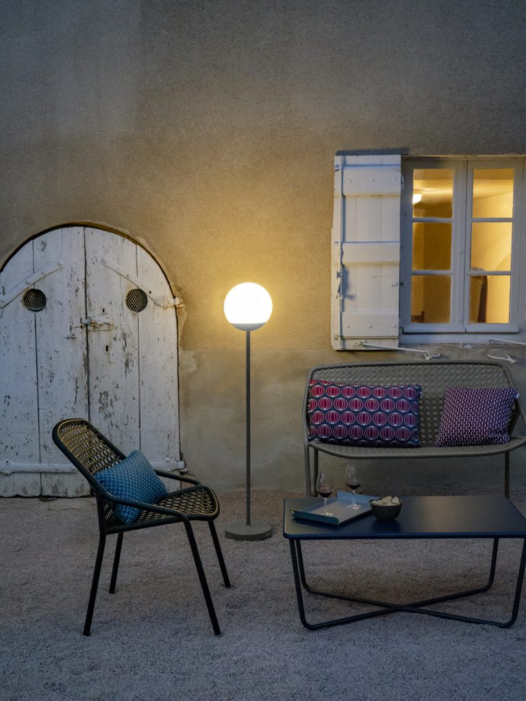 Une table avec des chaises et une lampe devant une fenêtre.
