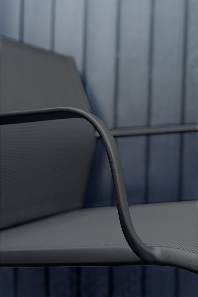 Un gros plan d'une chaise grise contre un mur bleu.