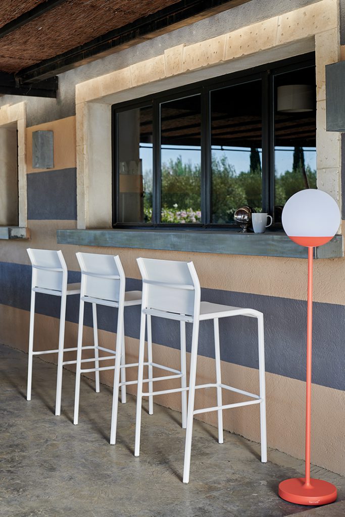 Quatre tabourets de bar blancs devant une fenêtre.