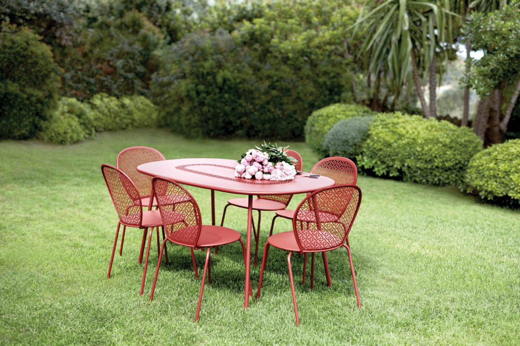 Une table et des chaises rouges dans un jardin.
