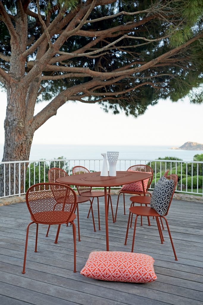 Une table et des chaises sur une terrasse avec vue sur l'océan.