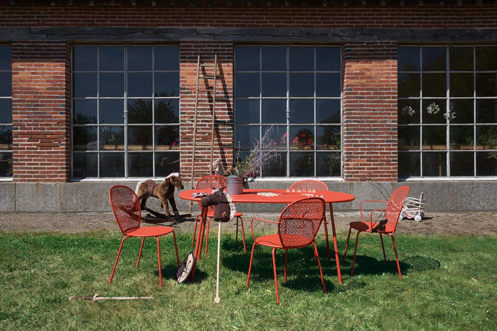 Une table et des chaises rouges sur l'herbe devant un immeuble.