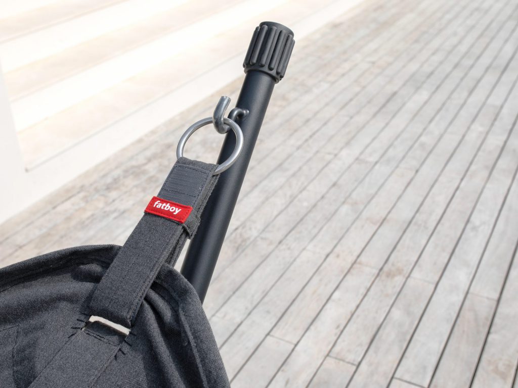 Un sac noir avec une poignée rouge sur une terrasse en bois.