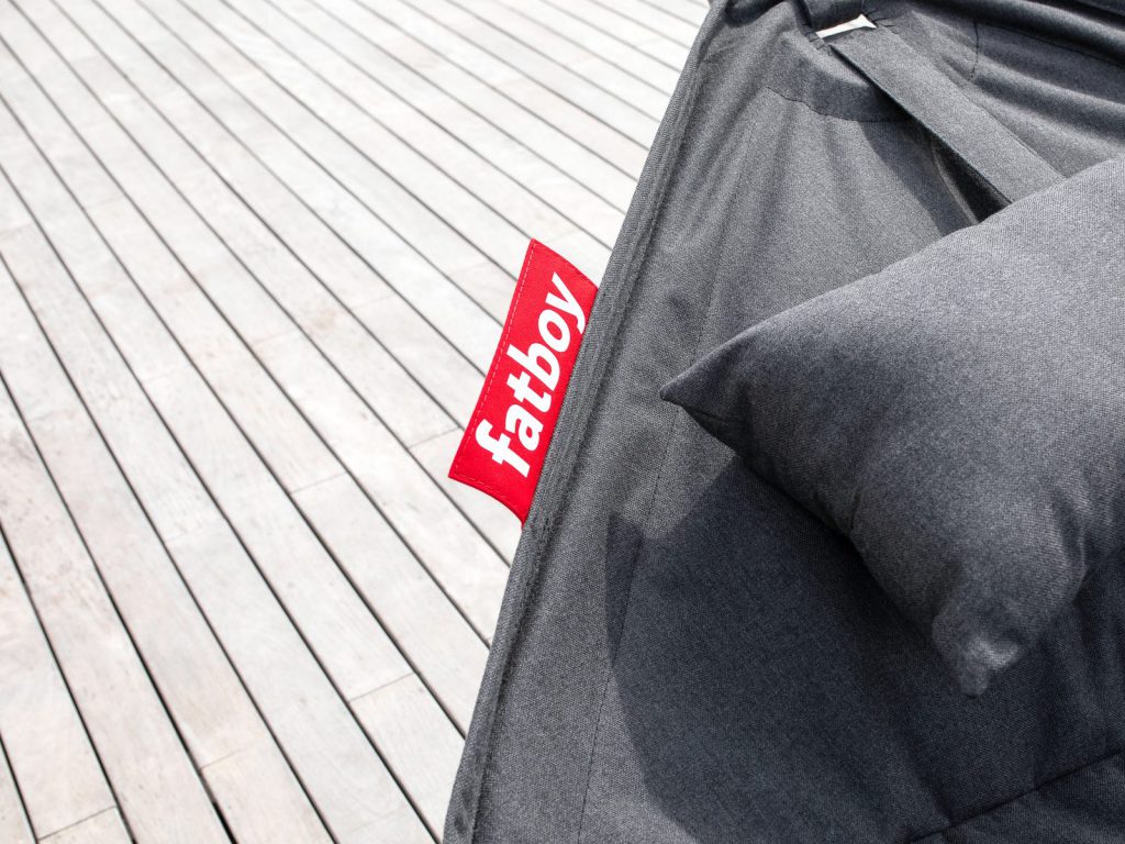 Un lit avec un oreiller dessus sur une terrasse en bois.