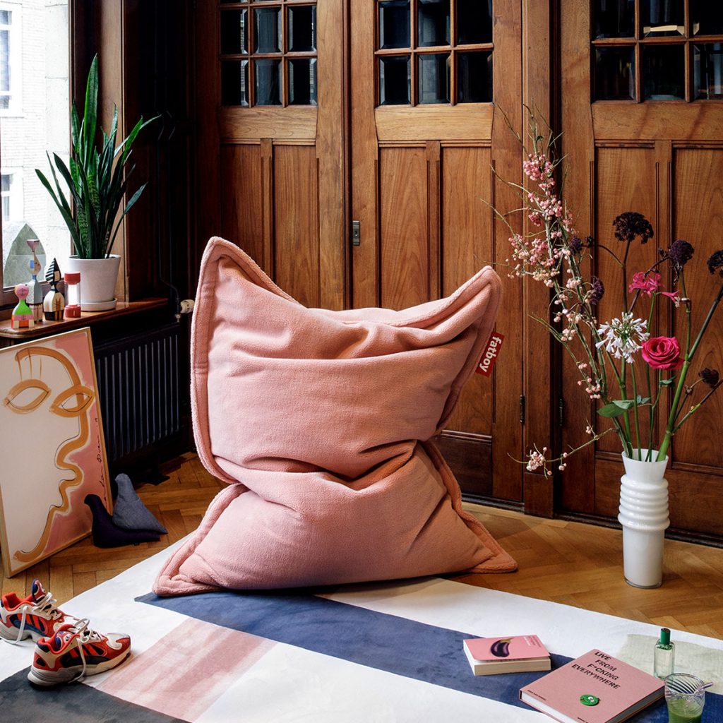 Un pouf rose posé sur un tapis dans une pièce.