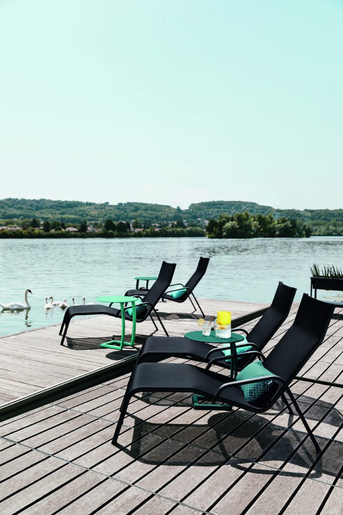 Un groupe de chaises longues sur un quai au bord d’un lac.