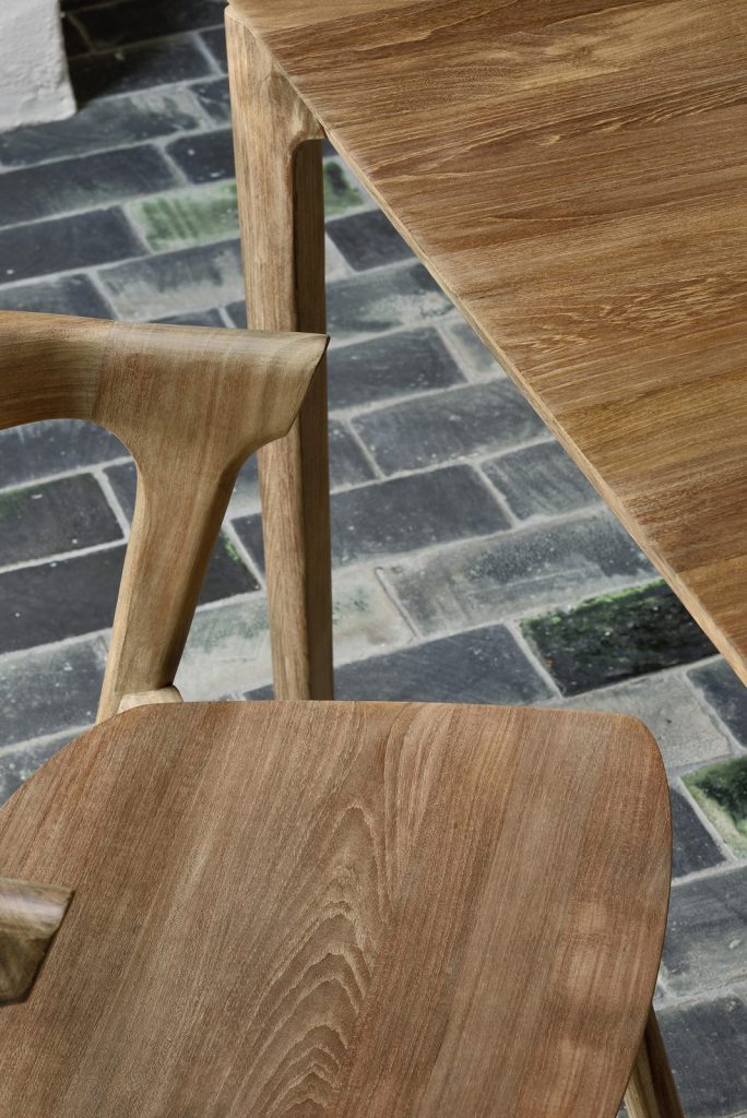Une table et des chaises en bois sur un sol en brique.
