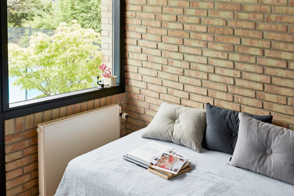 Un lit avec des oreillers devant une fenêtre.