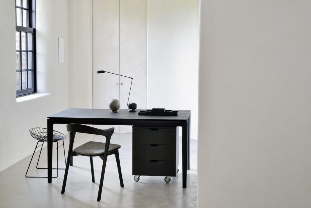 Un bureau noir dans une pièce aux murs blancs.