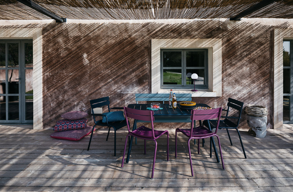 Chaises et tables de jardin Luxembourg en aluminium laque violettes et bleues sur une terrasse à l'ombre avec coussins