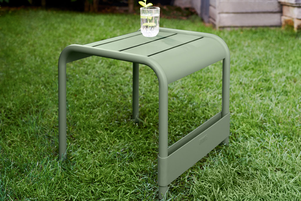 Repose pieds table d'appoint table basse pour jardin luxembourg en aluminium laque couleur cactus dans un jardin avec une plante dessus