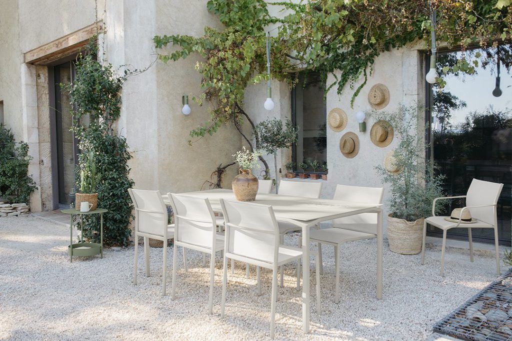 Un patio avec une table et des chaises devant une maison.