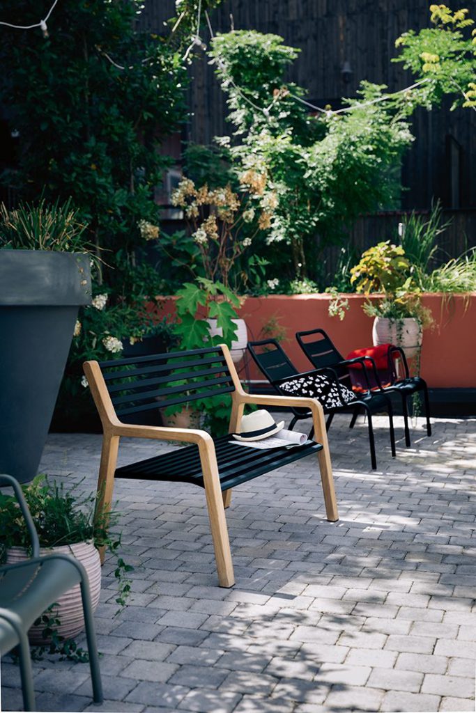 Un patio en brique avec un banc et quelques plantes en pot.