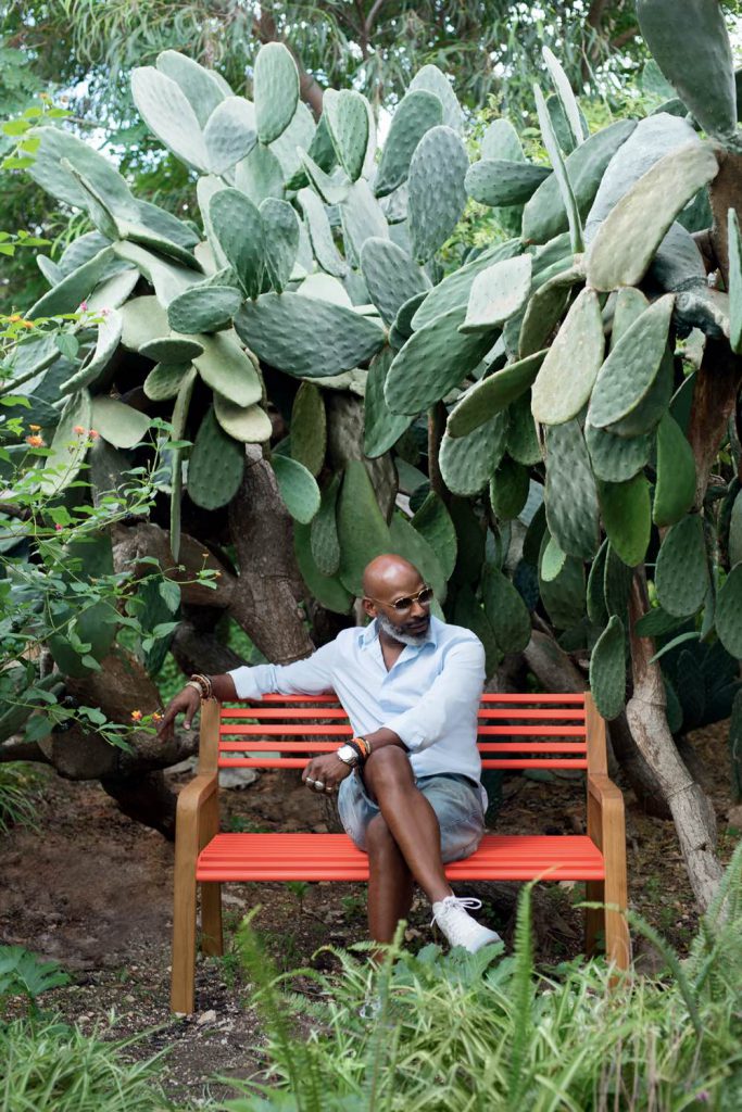 Un homme assis sur un banc devant des cactus.