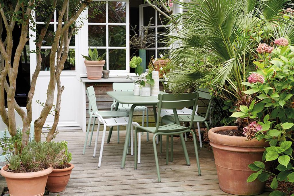 Un patio avec chaises vertes et plantes en pot.