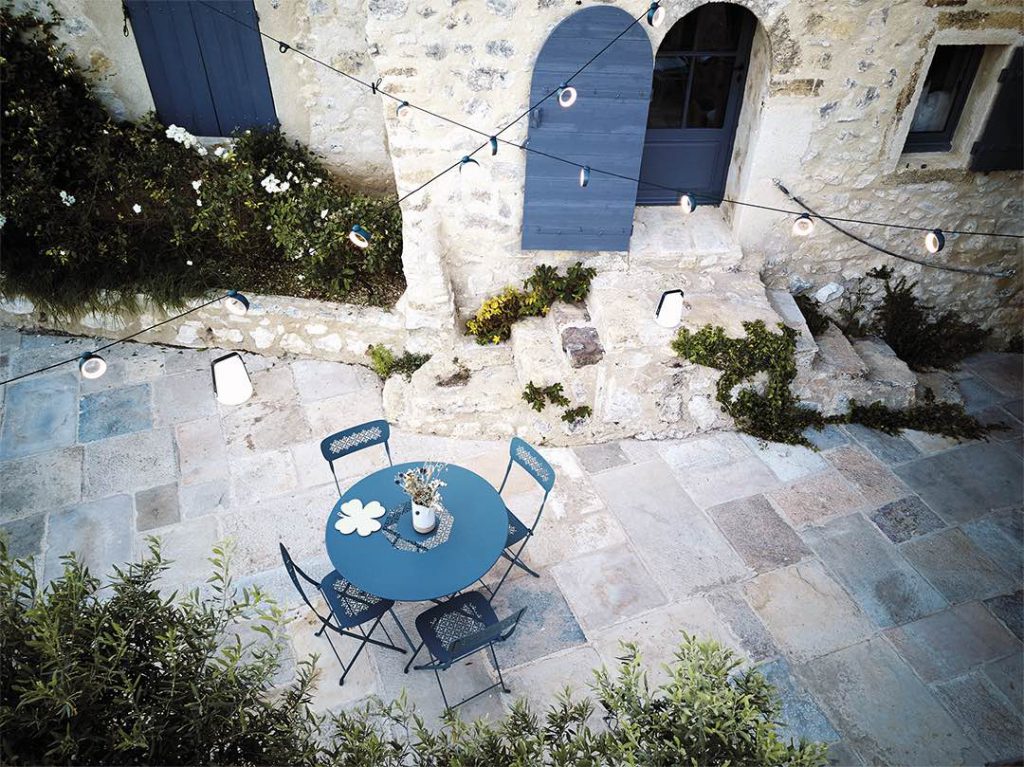 Une table et des chaises bleues sur un patio en pierre.