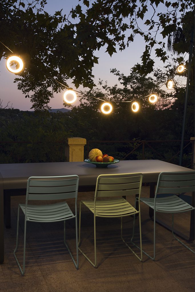 Une table avec quatre chaises sous une guirlande lumineuse.