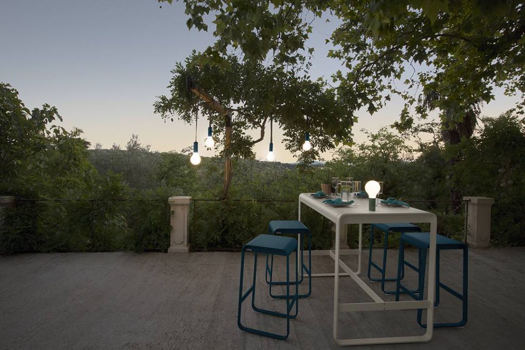 Une table avec des tabourets bleus et un arbre en arrière-plan.