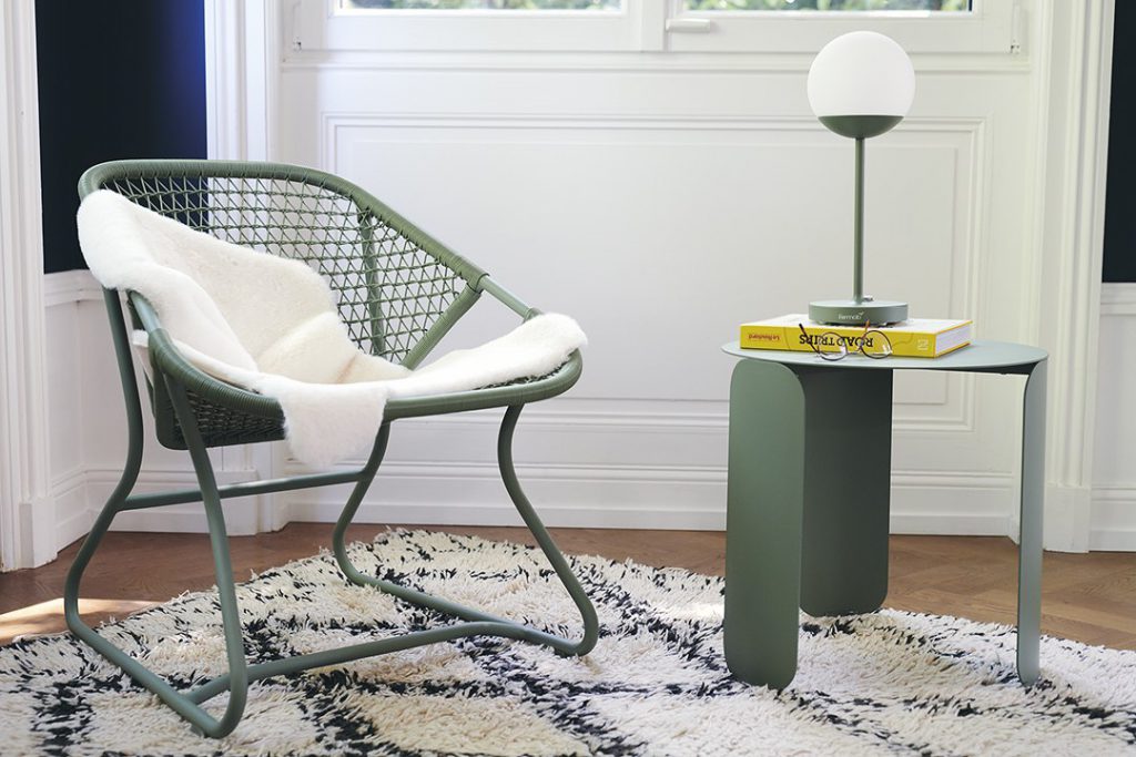 Une chaise et une table en osier vert dans une pièce avec une fenêtre.