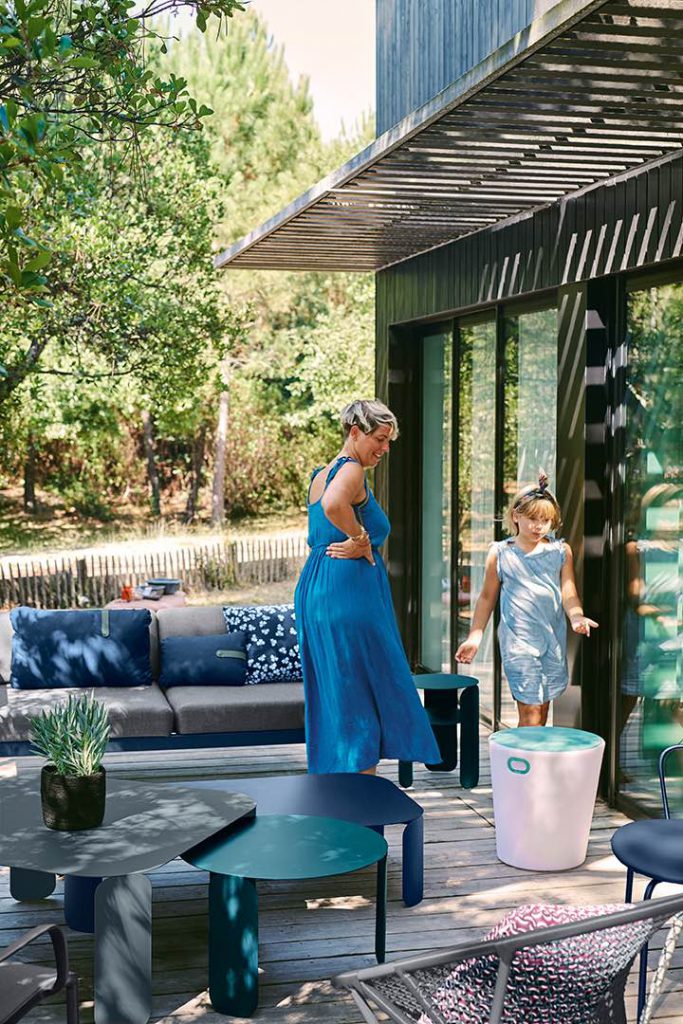 Une femme en robe bleue et une fille en robe bleue debout sur une terrasse en bois.